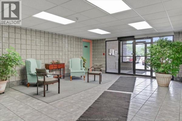 Interior lobby of the apartment building with tiled floors, seating area, and plants. - 8335 Wyandotte Street East Unit# 108, Windsor