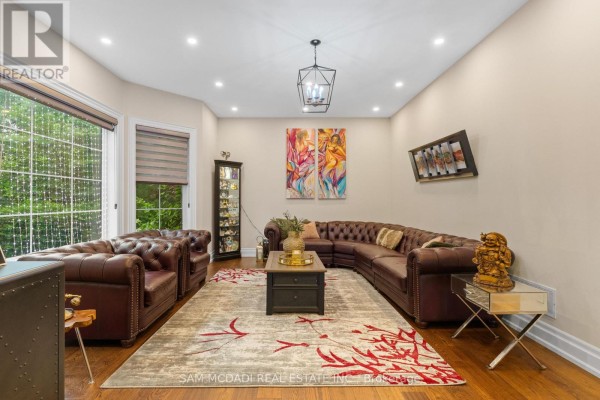 Living room featuring a large, tufted leather sectional sofa, patterned rug, and artwork on the wall. - 834 Edistel Crescent, Mississauga