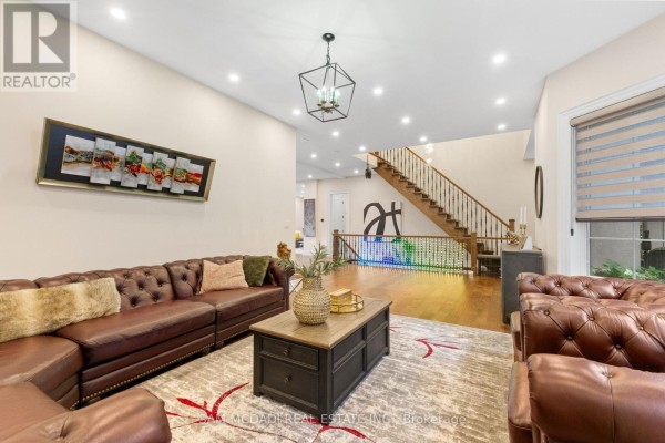 Another view of the living room, showcasing the sectional sofa, coffee table, and staircase in the background. - 834 Edistel Crescent, Mississauga