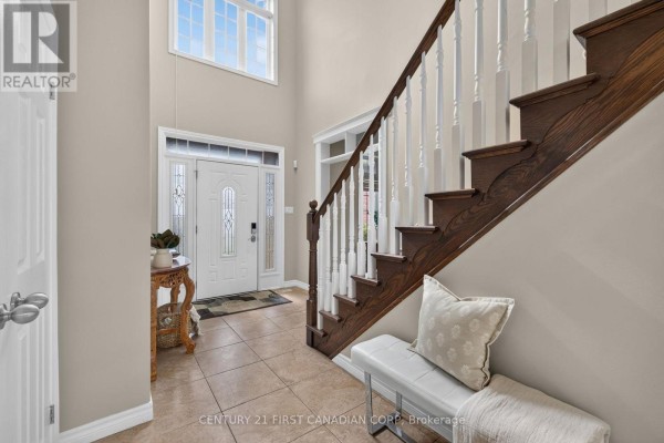 View of the foyer with a white front door, high ceiling window, and a dark wood staircase. - 834 Talisman Crescent, London South