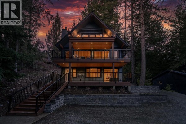 Three-story blue house with wood accents and balconies at dusk. - 8353 Rainbow Drive, Whistler