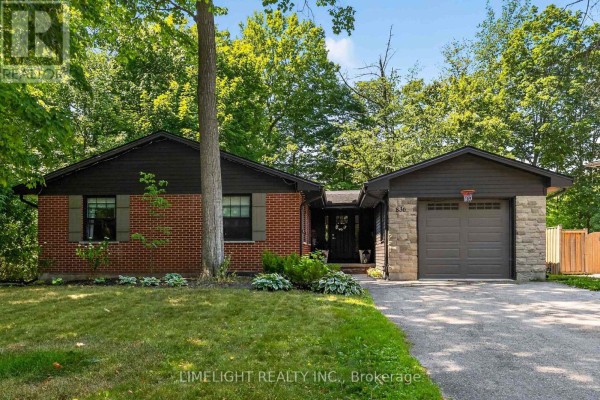 Close-up front view of a brick bungalow with dark wood siding, stone accents, and an attached garage. - 836 Manchester Road, London North