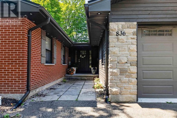 Detailed view of the entrance walkway, brick siding, stone pillar with house number 836, and garage door. - 836 Manchester Road, London North