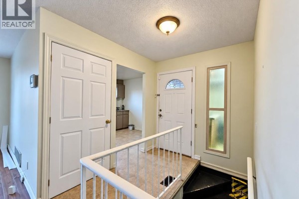 Interior foyer with white doors, a white railing leading downstairs, and a glass-paned front door. - 8370 Gregory, Windsor