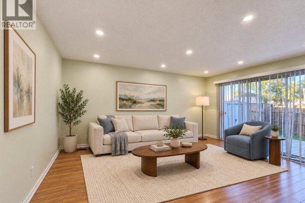 Living room with light green walls, a large sectional sofa, coffee table, and sliding glass doors. - 8370 Gregory, Windsor