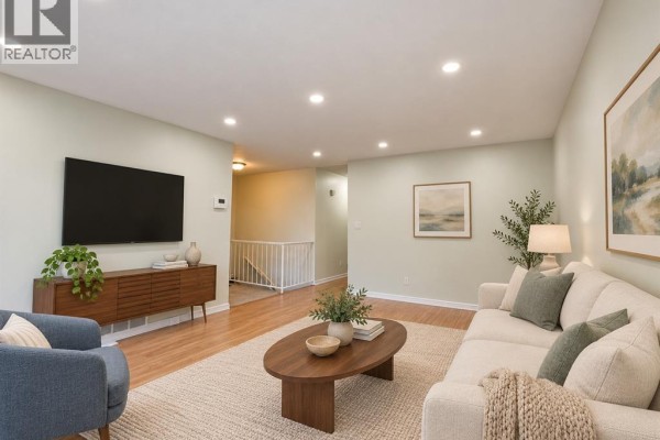 Living room with a sectional sofa, coffee table, armchair, television, and a view of the staircase. - 8370 Gregory, Windsor