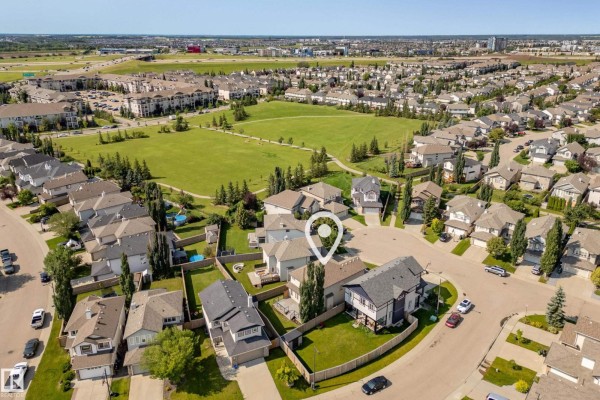 Aerial view of a suburban neighborhood with houses, streets, and a park. - 8385 Shaske Cr Nw, Edmonton