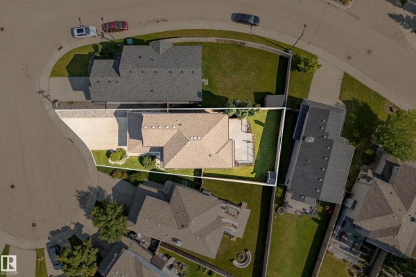 Aerial view of a residential lot with a house, driveway, and surrounding properties. - 8385 Shaske Cr Nw, Edmonton