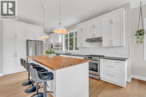White kitchen with wood island, stainless steel range, subway tile backsplash, and pendant lights. - 8388 Princeton Summerland Road, Summerland