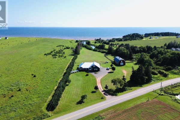 Aerial view of a property with a house, barn, fields, and ocean in the distance. - 8395 Rte 19, Bonshaw