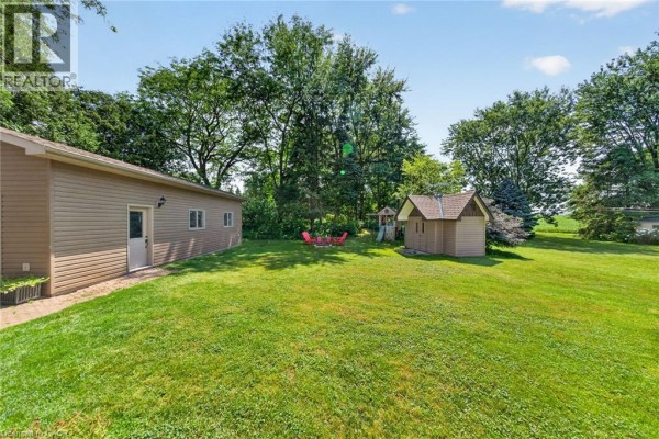 Backyard with a detached garage, shed, small playset, and green lawn. - 8399 Dickenson Road E, Mount Hope