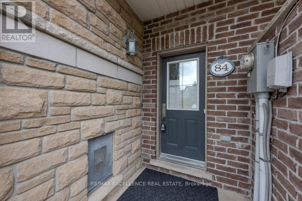 Front entrance of townhouse with grey door, sidelight, and brick and stone facade. - 84 - 110 Cedar Lake Crescent, Brampton