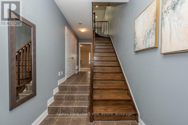 Interior hallway with staircase, tiled flooring, and decorative mirrors and artwork. - 84 - 110 Cedar Lake Crescent, Brampton