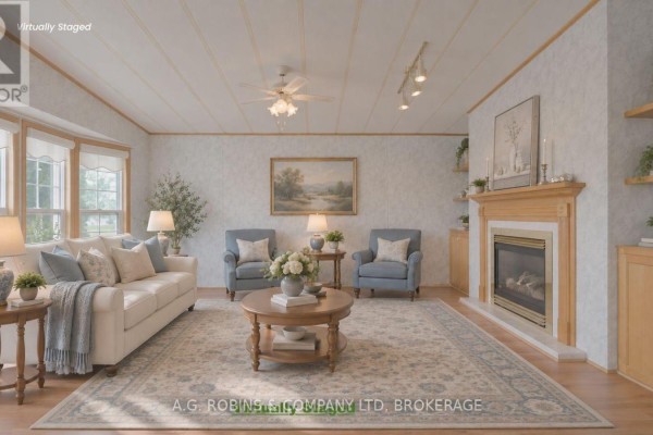 Virtually staged living room with a sofa, two blue armchairs, a coffee table, a fireplace, and a large rug on wood flooring. - 84 - 3033 Townline Road, Fort Erie
