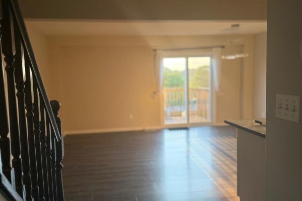 View from the hallway into a living area with a dark wood staircase and a patio door. - 84 - 355 Fisher Mills Road W, Cambridge