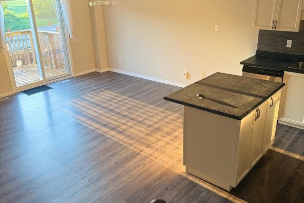 Living area with dark wood floors, beige walls, a kitchen island, and a patio door. - 84 - 355 Fisher Mills Road W, Cambridge