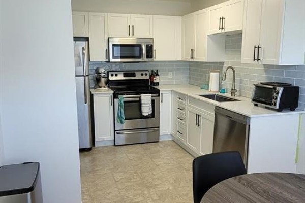 White kitchen with stainless steel appliances, subway tile backsplash, and light gray countertops. - 84 717 Aspen Rd, Comox