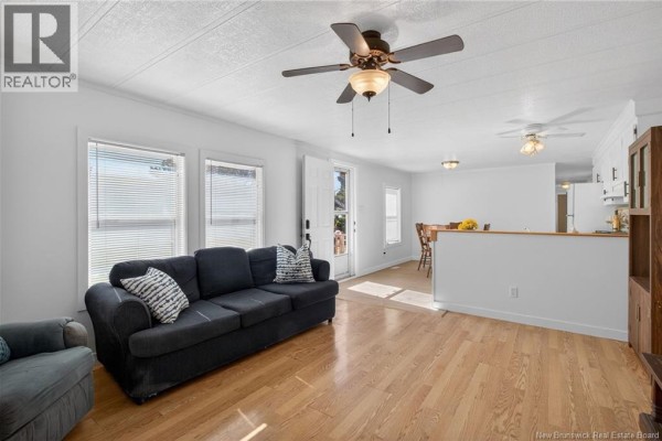 Living room and dining area with a sofa, windows, and a view into the kitchen and dining room. - 84 Biddington, Moncton