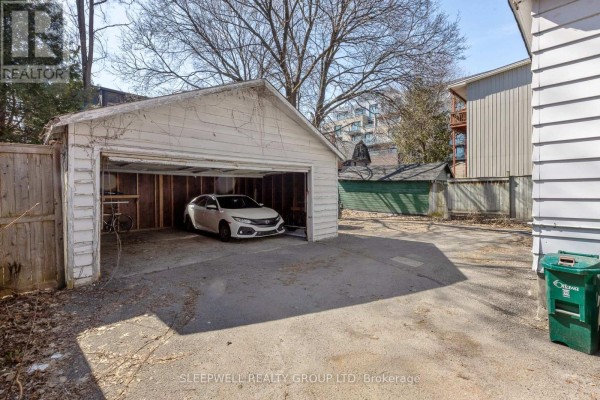 Bedroom with a queen-size bed, hardwood floors, and a large mirror. - 84 Fourth Avenue, Ottawa