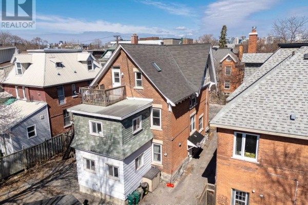 Exterior view of a red brick multi-family house with white trim on a snowy day. - 84 Fourth Avenue, Ottawa