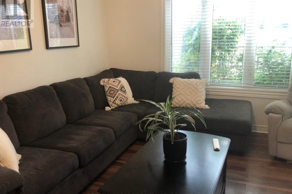 Living room with a large sectional sofa, coffee table, and blinds on window. - 84 Mcbride Drive, St  Catharines