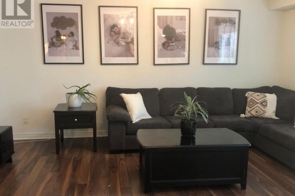 Living room with a dark sectional sofa, coffee table, and family photos on wall. - 84 Mcbride Drive, St  Catharines