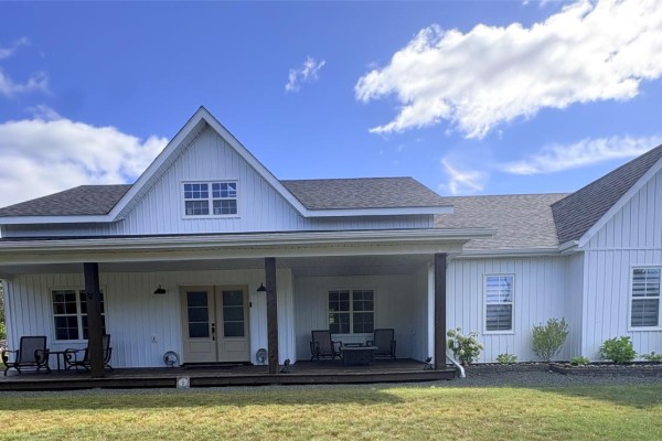 Front view of white house with a wide covered porch featuring seating and double doors. - 84 Road To The Isles Road, Lewisporte