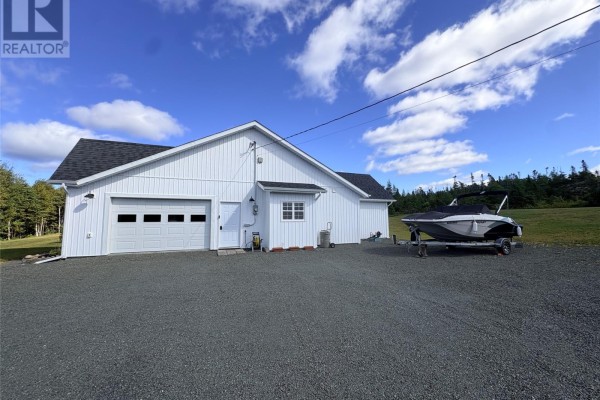 Side view of white house with an attached garage, a white garage door, and a boat on a trailer. - 84 Road To The Isles Road, Lewisporte
