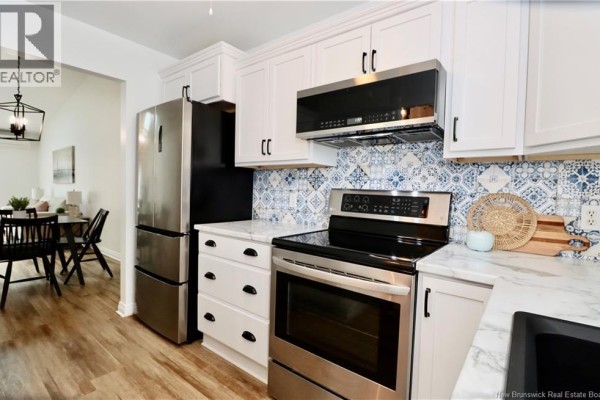 Kitchen with white cabinets, stainless steel appliances, and a view of a dining area. - 84 Seaman Street Unit# 5, Moncton