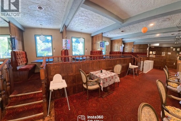 Restaurant dining area with red carpet, wooden dividers, tables, and windows. - 8405 Byng Rd, Port Hardy