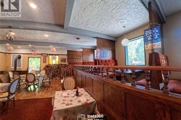 Restaurant dining area with red carpet, wooden booths, tables, and a window view. - 8405 Byng Rd, Port Hardy