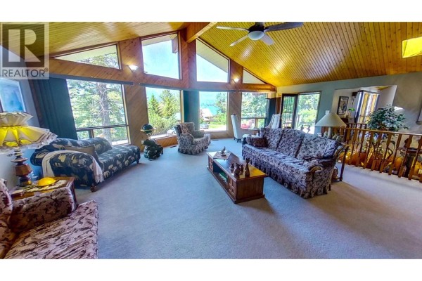 Living room with patterned sofas, wood-paneled vaulted ceiling, and large windows with a mountain view. - 8408 Richardson Crescent, Canal Flats