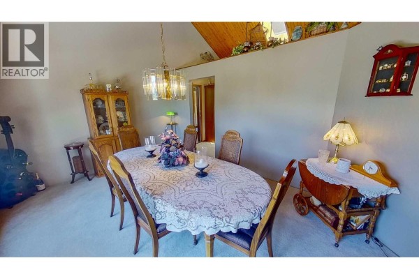 Formal dining room with a large oval table, wooden hutch, and chandelier. - 8408 Richardson Crescent, Canal Flats