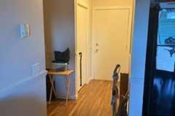 Apartment hallway with hardwood floors, beige walls, and doors. - 8412, 304 Mackenzie Way Sw, Airdrie