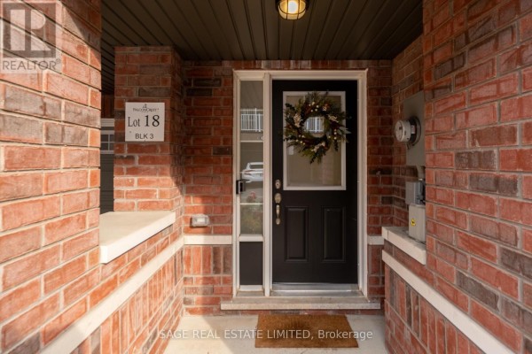 Front entrance of a brick townhouse with a black door and wreath. - 842 Atwater Path, Oshawa