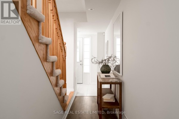 Hallway with white walls, a wooden staircase with beige carpet, and a console table. - 842 Atwater Path, Oshawa