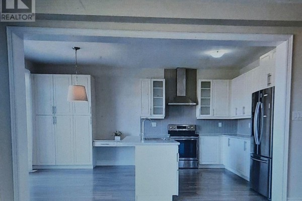 Modern white kitchen with stainless steel appliances, island, and light wood flooring. - 8421 Sweet Chestnut Drive, Niagara Falls