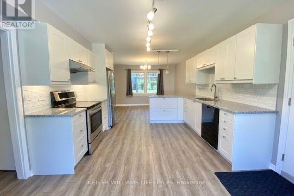 Modern kitchen with white cabinets, granite countertops, stainless steel appliances, and a large island. - 843 Driftwood Road, London North