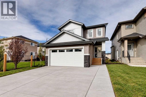 View of a house exterior with a paved driveway and neat green grass. - 844 Hampshire Crescent Ne, High River