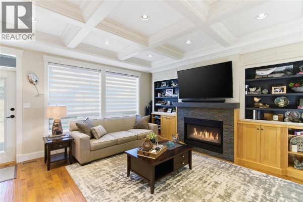Living room with a gas fireplace, built-in shelving, coffered ceiling, and large windows. - 844 Mulholland Dr, French Creek