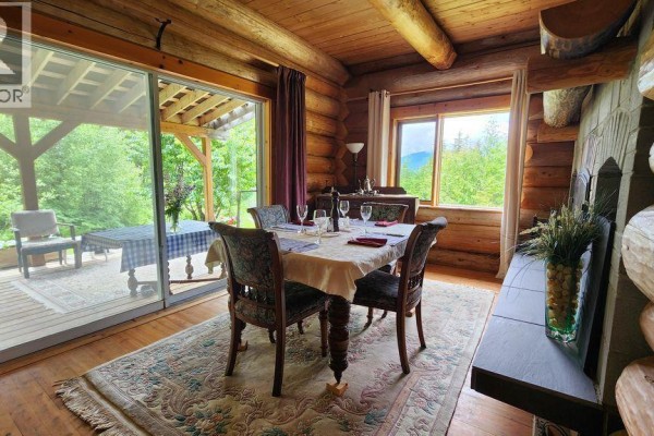Dining area with a table set for four, sliding glass doors to a deck, and log walls. - 8470 Red Mountain Road, Silverton