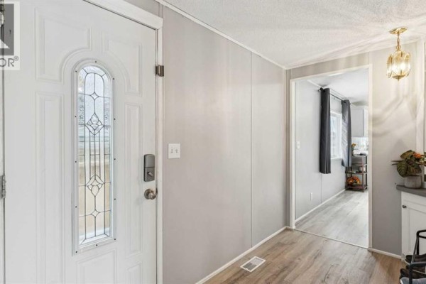 View of the front entrance and hallway with a textured white door and light gray walls. - 848 Madison Drive, Irricana