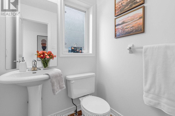 Powder room with pedestal sink, toilet, and a small window. - 849 Joe Persechini Drive, Newmarket