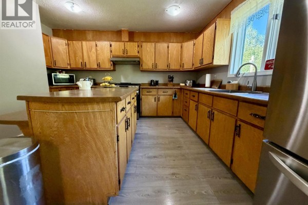 U-shaped kitchen with light oak cabinets, butcher block countertops, and a large central island. - 8490 Louise Drive, Prince George