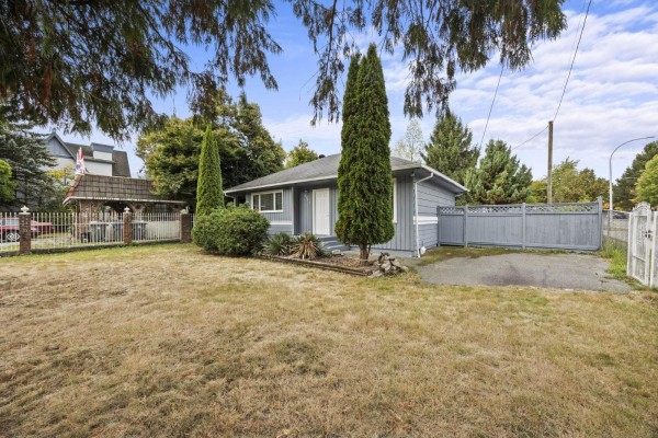 Side view of a light blue bungalow with a fenced yard and driveway access. - 8495 164 Street, Surrey