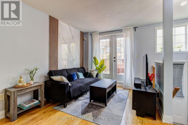 Living room with a black sofa, coffee table, patterned rug, and french doors. - 85 - 2 Hedge End Road, Toronto