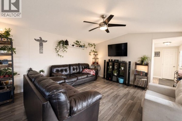 Living room with dark leather sectional, light sofa, television, and decorative shelves. - #85 9824 104 Avenue, Clairmont