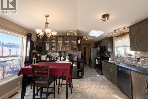 Kitchen and dining area with dark cabinets, stainless steel appliances, and a table set with a red cloth. - #85 9824 104 Avenue, Clairmont