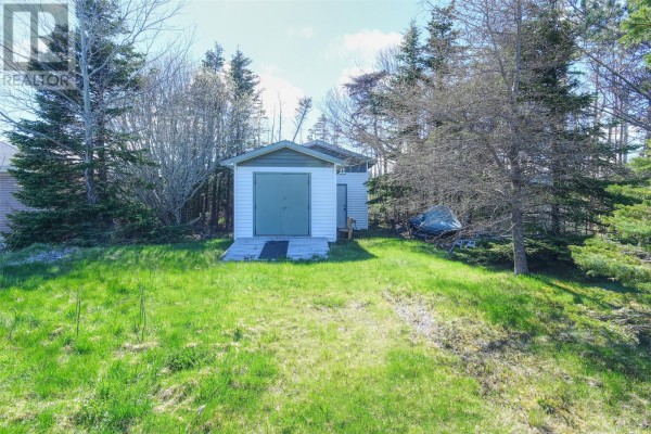 Detached garage with a light green door and white trim surrounded by trees. - 85 Airport Road, St  John S
