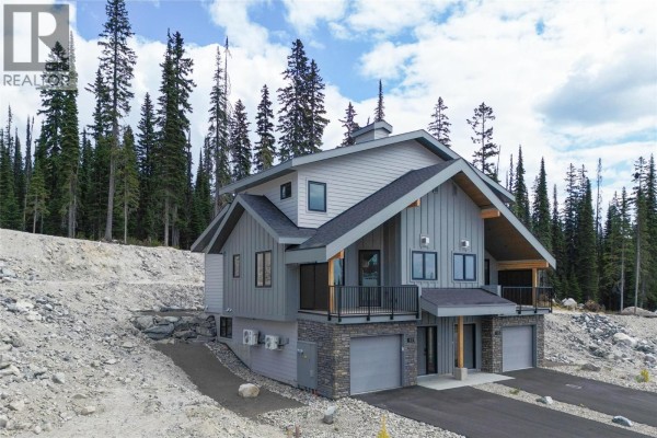 Duplex exterior with grey siding, stone accents, and two garages. - 85 Creekside Trail, Big White